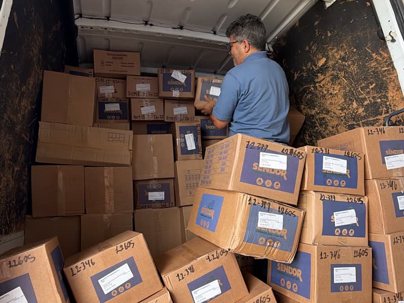 Funcionário da Sêndor carregando caixas de produtos no furgão de entrega