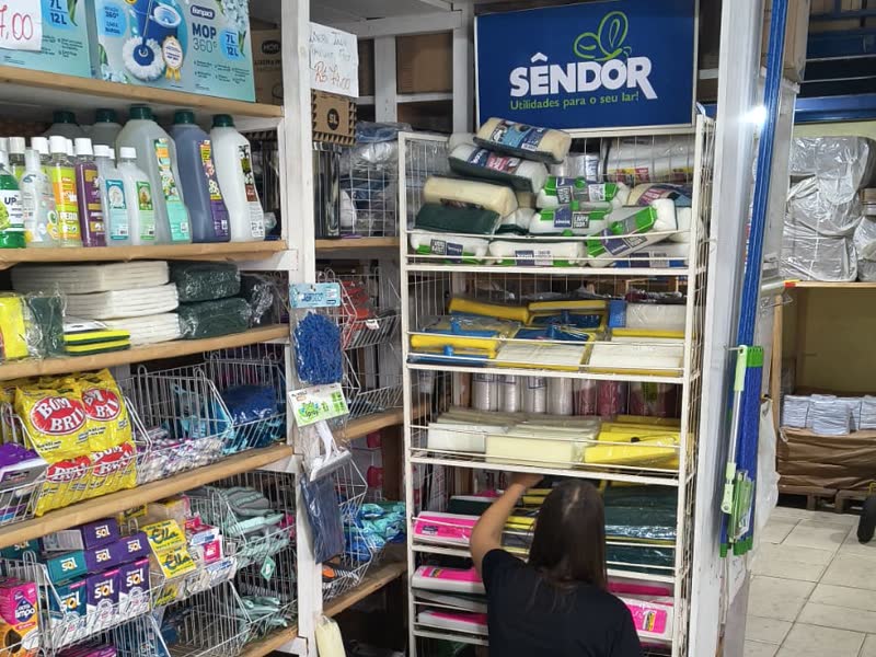 Expositor Sêndor sendo reposto dentro da loja de um cliente, com caixas da marca ao lado
